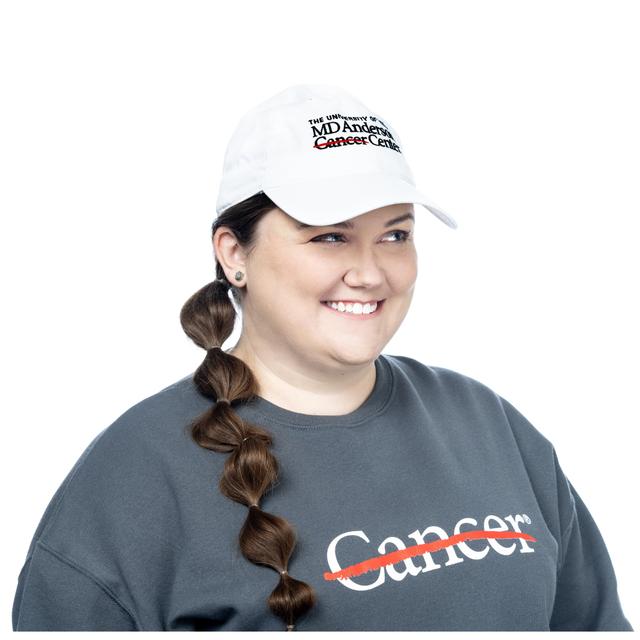 MD Anderson employee wearing a white baseball cap with the MD Anderson logo displayed in black on the front.